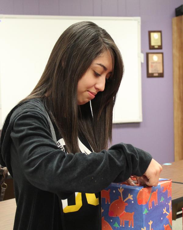 Wrapping for others--
Senior Geovanna Espino tapes wrapping  paper on a gift for a client at the Mental Health and Mental Retardation Center. The advanced cosmetology students will play elves and deliver the gifts today.