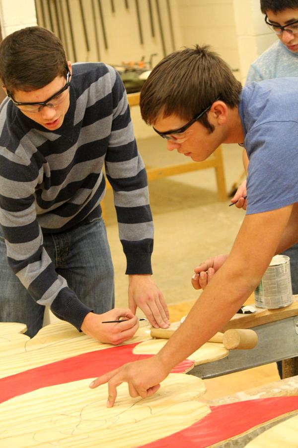 Inside the lines--
Industrial arts junior Royce Snethen and freshman Dakota Baker discuss paint placement on one of the wooden Santas in the display the classes are making to place outside the school. The project involved cutting out the wooden figures from patterns and painting them.