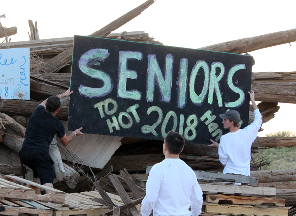 Top of the heap--
Seniors Dave Dyck Wall, Alex Gonzales and Clayton Medlin position a senior sign on the wood pile before the homecoming bonfire at Gaines County Park on Sept. 21.
