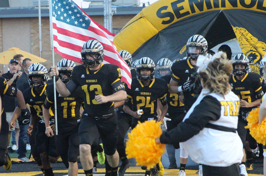Leading the Tribe--Senior linebacker Cade Barnard carries the American flag as the Indians take the field at the homecoming game versus Amarillo River Road.