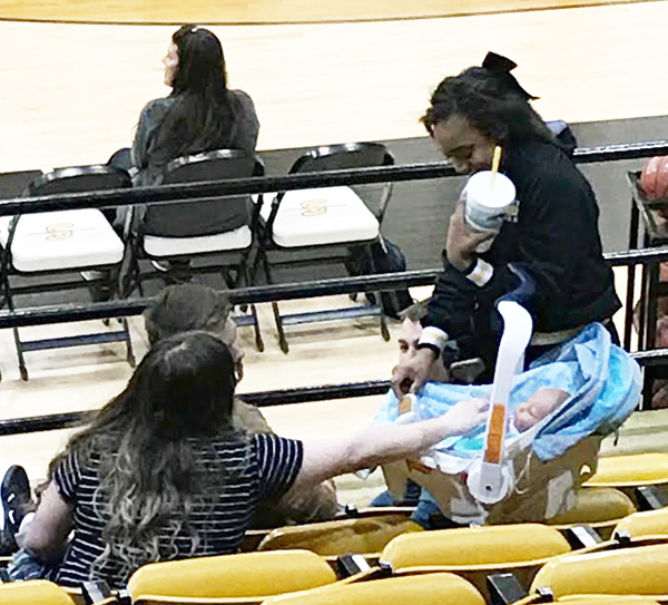 Proud mom--
Sophomore Mady Carter shows off her newborn to friends at a basketball game in February. Carter had to arrange babysitting for the newborn simulator while she cheered for the varsity games.