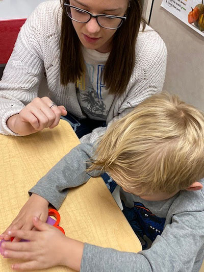 Hands-on donation--SkillsUSA culinary senior Evalin Friesen and an F.J. Young Elementary pre-K student play with play dough donated by the SkillsUSA chapter and the culinary classes on Nov. 13.