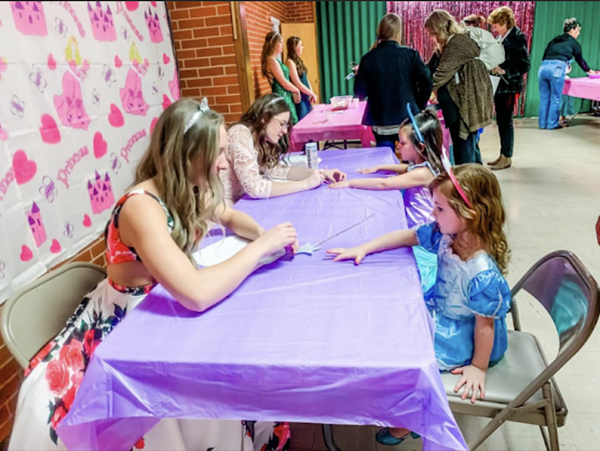 Playing with princesses--SkillsUSA Culinary seniors Rita Klassen and Lisa Rempel paint tiny princesses nails during their tea party promotion on Jan. 23 at First Methodist Church. 