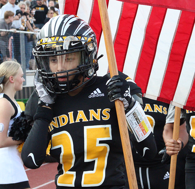Honoring others--Junior defensive back Joe Gutierrez carries a flag to honor fallen veterans during the sept. 10 game. The Indians would win the preseason match up with Denver City, 22-18.