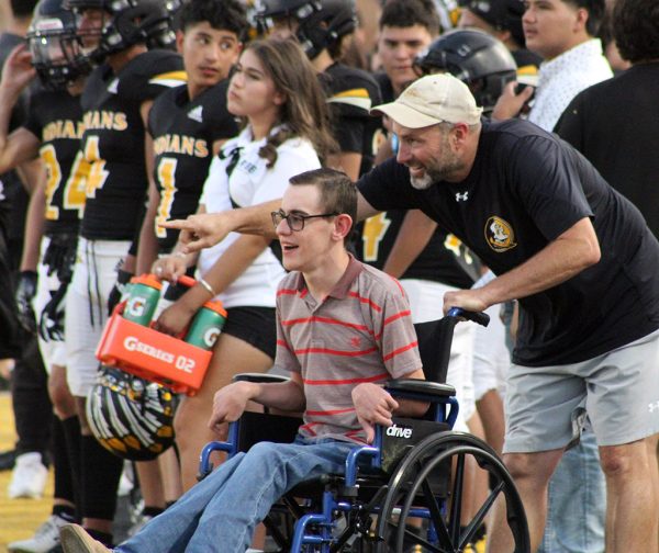 One of the team--
Coach Steven Flowers explains what’s happening on the field to junior Poncho Unrau during the JV football game on Sept. 28. Unrau had never attended a live game, so two of the coaches made it happen.