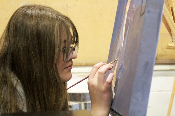 Delicate details--Sophomore Anna Harder leans in to take tiny strokes on her painting for VASE competition during fourth period on Jan. 12. Harder entered two pieces in the competition this year.
