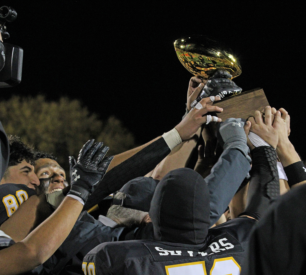 Going for gold--Senior linemen Nate Trujillo and Reno Deleon reach for the trophy after the Indians defeated Levelland to become bi-district champions on Nov. 15.