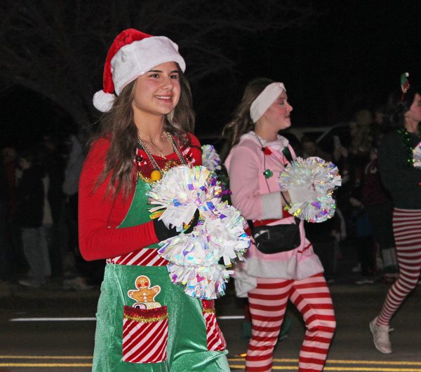 Festive outfit--Junior Kelly Heide boasts gingerbread overalls as she marches in the Christmas parade on Dec. 12. The cheerleaders chose festive clothing as elves for the event.