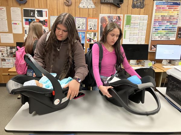 Babies on board--Seniors Armine Sandoval and Izariah Escontrias pick up their babies after lunch from their teacher babysitter in April. The babies were a three-day learning lesson in child development.