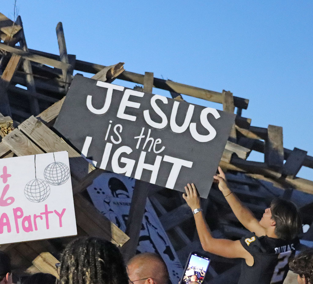 Gimme a sign--Senior Austin Olivas carefully places his sign on the bonfire pile on Sept. 11.