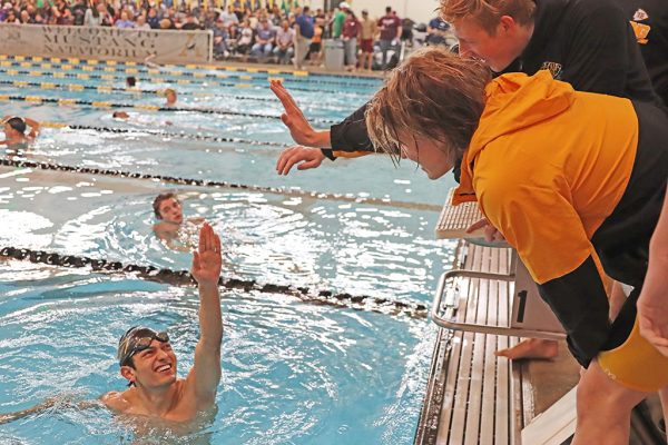 Congratulations--Teammates high five senior Carlos Arzate after he swims one of two individual personal records at regionals in Andrews on Jan. 31. Arzate would qualify for state for a fourth year in a row in four events.